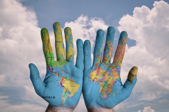 Two hands are painted with a world map, displayed against a background of a cloudy sky, symbolizing global talent acquisition and effective hiring strategies.